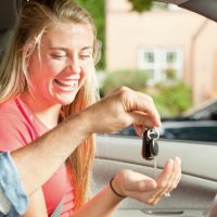 Young Driver Receiving Car Key from Parent Sitting in Vehicle