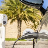 Electric car plugged by cable to charging station